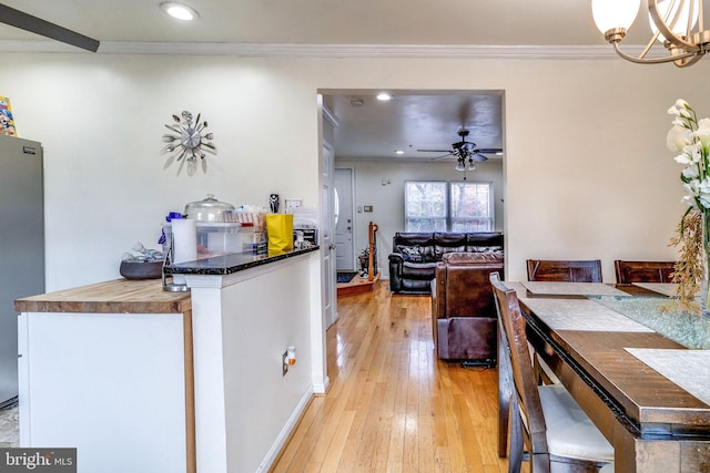 kitchen featuring ornamental molding, ceiling fan with notable chandelier, light hardwood / wood-style flooring, and stainless steel refrigerator