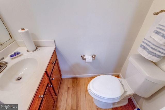 bathroom with toilet, vanity, and wood-type flooring