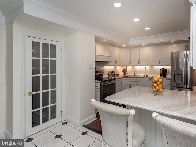 kitchen featuring a kitchen bar, sink, ornamental molding, appliances with stainless steel finishes, and premium range hood