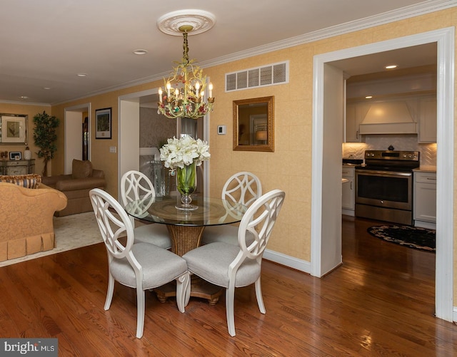 dining space featuring dark hardwood / wood-style flooring, crown molding, and an inviting chandelier