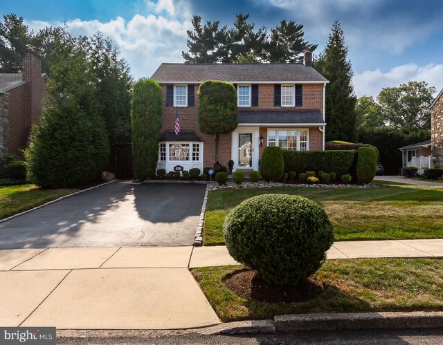 colonial-style house featuring a front lawn