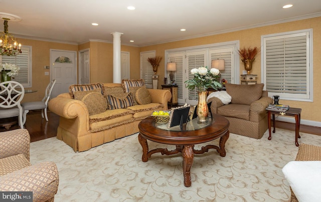 living room featuring ornate columns, light hardwood / wood-style flooring, a chandelier, and crown molding