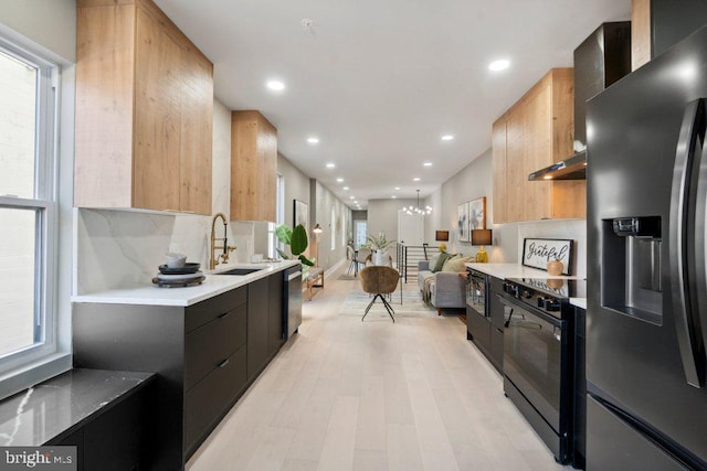 kitchen featuring light brown cabinets, appliances with stainless steel finishes, a chandelier, light wood-type flooring, and sink