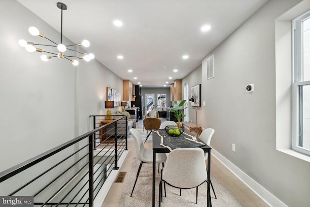 dining area with a notable chandelier, light wood-type flooring, and a wealth of natural light