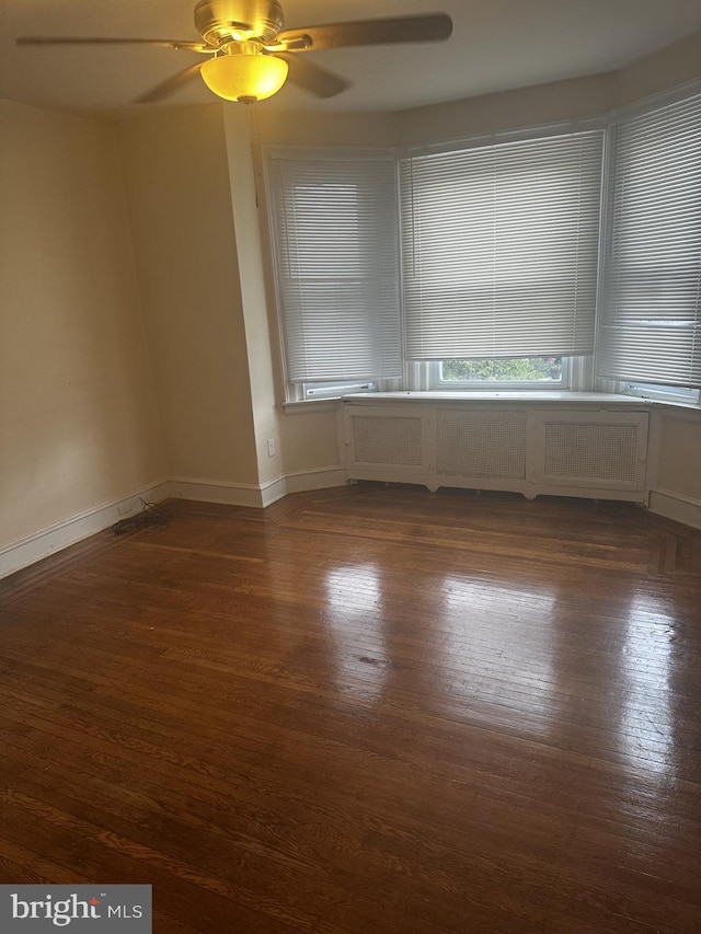 spare room with radiator, ceiling fan, and dark hardwood / wood-style flooring