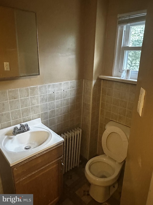 bathroom with vanity, radiator heating unit, toilet, and tile walls