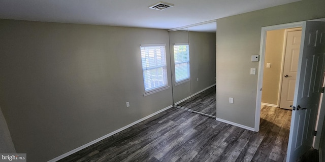 unfurnished bedroom with a closet and dark hardwood / wood-style flooring