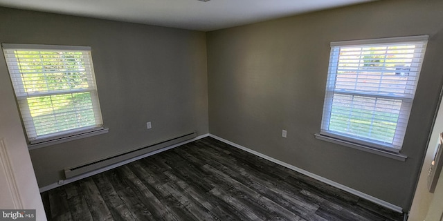 empty room featuring a baseboard heating unit, a healthy amount of sunlight, and dark wood-type flooring