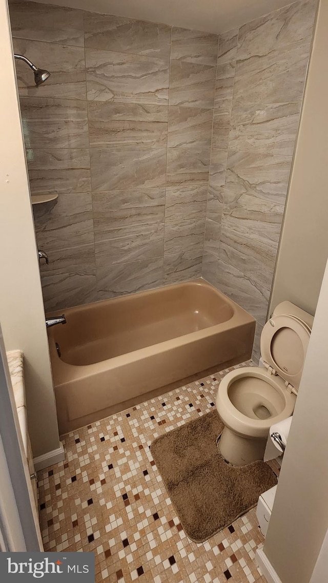 bathroom with toilet, tiled shower / bath combo, and tile patterned flooring