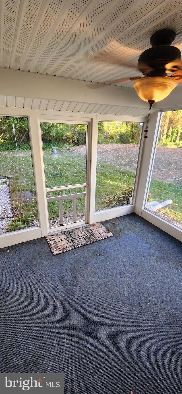 unfurnished sunroom featuring ceiling fan and a wealth of natural light