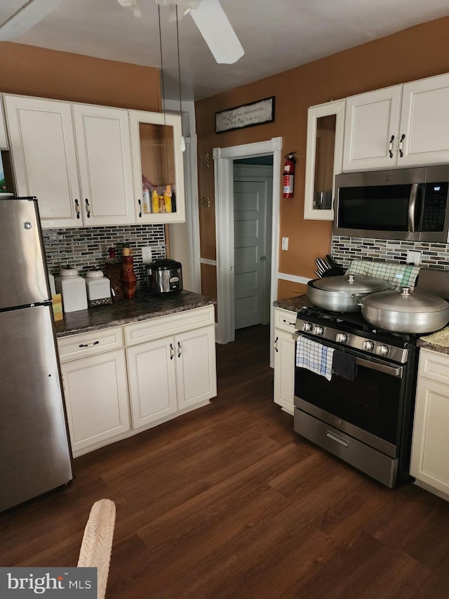 kitchen featuring white cabinets, tasteful backsplash, dark hardwood / wood-style flooring, appliances with stainless steel finishes, and decorative light fixtures