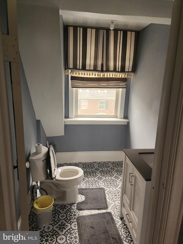 bathroom with toilet, vanity, and tile patterned flooring