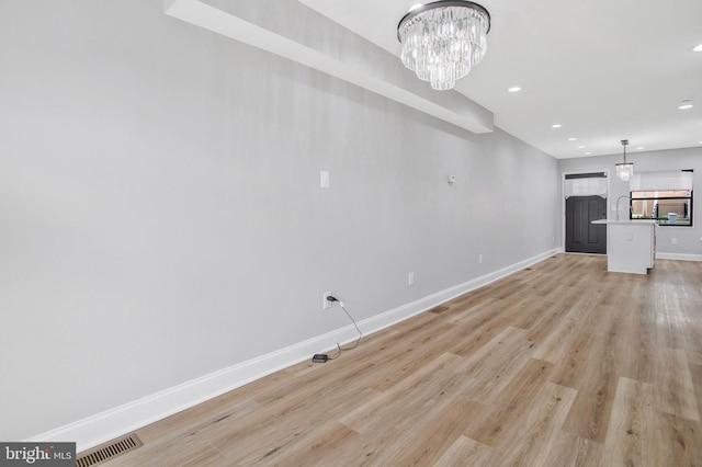 unfurnished living room with light hardwood / wood-style floors and an inviting chandelier