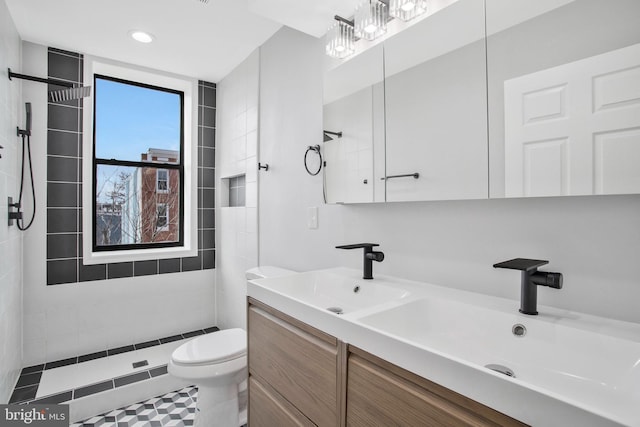 bathroom featuring tiled shower, vanity, toilet, and tile patterned flooring