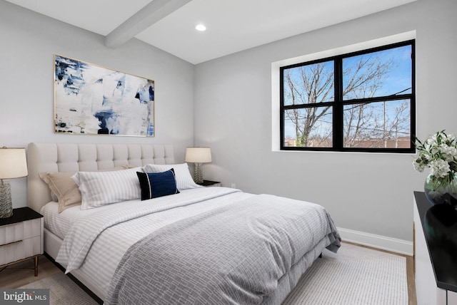 bedroom with beamed ceiling and light hardwood / wood-style floors