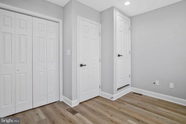 unfurnished bedroom featuring light hardwood / wood-style flooring and a closet