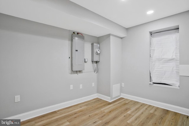 spare room featuring electric panel and light hardwood / wood-style flooring