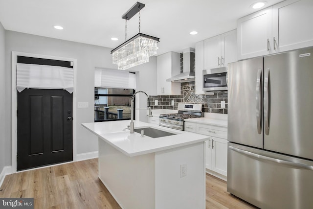 kitchen featuring a kitchen island with sink, sink, hanging light fixtures, white cabinetry, and stainless steel appliances