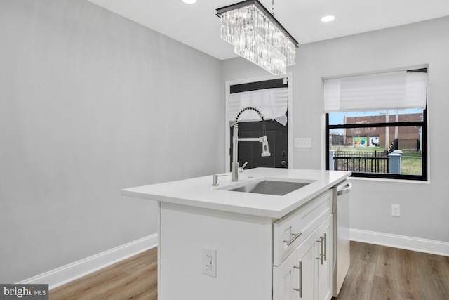 kitchen featuring sink, a chandelier, light hardwood / wood-style floors, a kitchen island with sink, and white cabinets