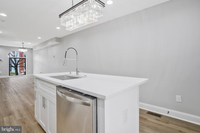 kitchen featuring white cabinetry, dishwasher, sink, hanging light fixtures, and a center island with sink