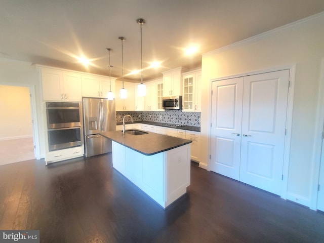 kitchen with appliances with stainless steel finishes, sink, decorative light fixtures, a center island with sink, and white cabinets