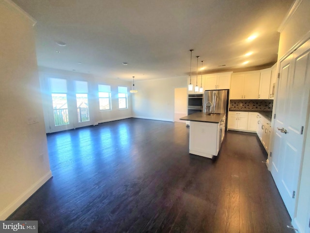 kitchen featuring decorative backsplash, stainless steel fridge, dark hardwood / wood-style flooring, a kitchen island with sink, and white cabinetry