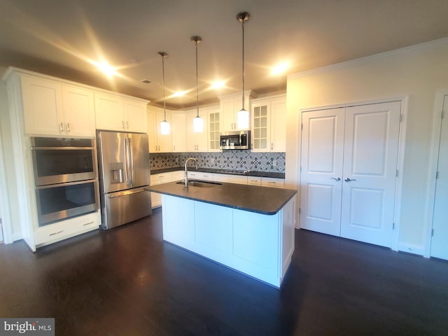 kitchen with appliances with stainless steel finishes, sink, decorative light fixtures, a center island with sink, and white cabinetry