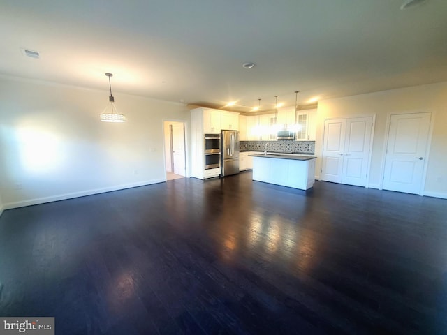 kitchen with dark wood-type flooring, hanging light fixtures, white cabinets, and stainless steel appliances