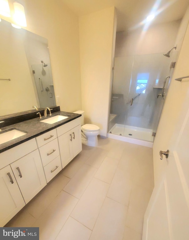 bathroom with tile patterned flooring, vanity, a shower with shower door, and toilet