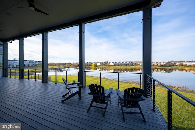 deck with ceiling fan, a water view, and a yard