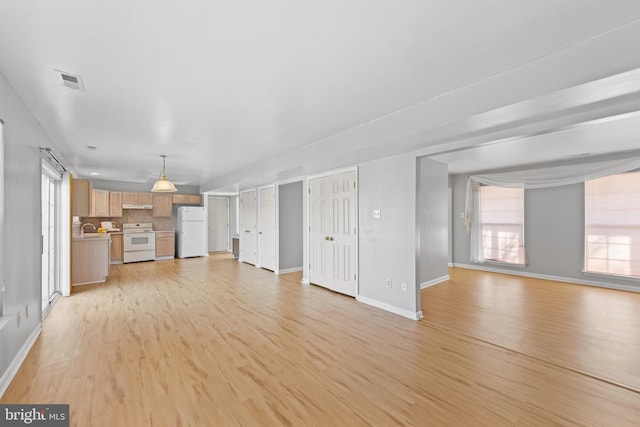 unfurnished living room featuring light wood-type flooring and sink