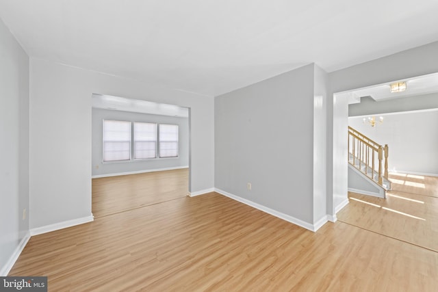 unfurnished room featuring light wood-type flooring and an inviting chandelier