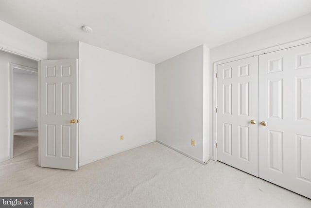 unfurnished bedroom with a closet and light colored carpet