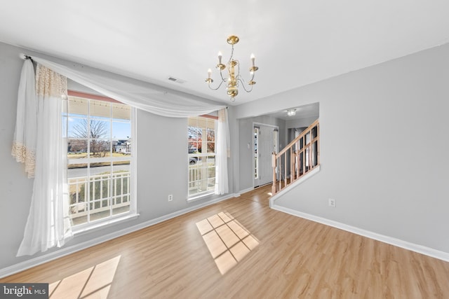 empty room featuring hardwood / wood-style floors, plenty of natural light, and a notable chandelier