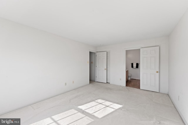 unfurnished bedroom featuring connected bathroom and light colored carpet