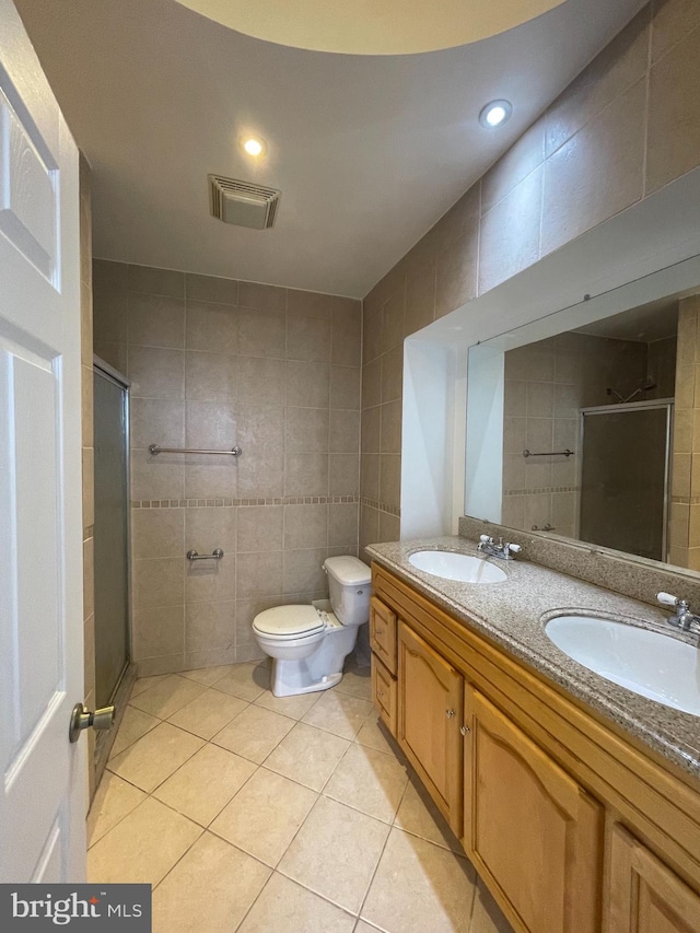 bathroom with toilet, vanity, tile walls, and a shower with door