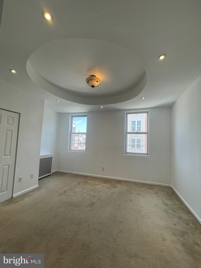 carpeted empty room featuring a raised ceiling