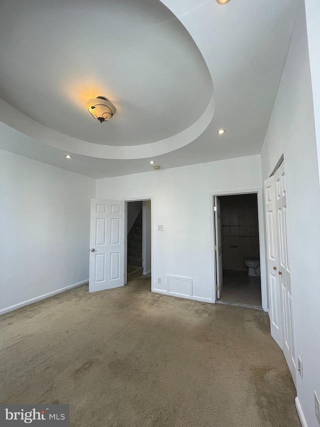 carpeted spare room with a raised ceiling