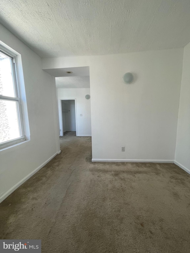 spare room with dark carpet and a textured ceiling