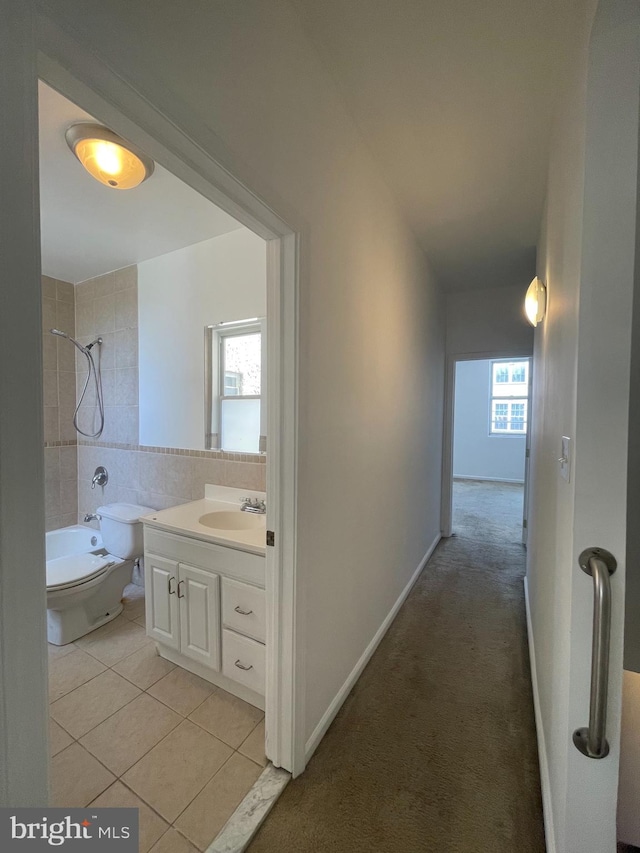 hallway with a wealth of natural light, sink, and light tile patterned floors