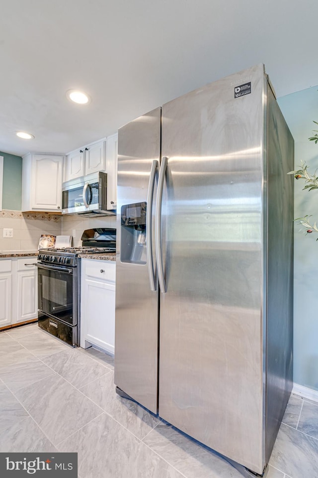 kitchen with white cabinetry, tasteful backsplash, stainless steel appliances, and dark stone counters