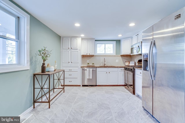 kitchen with white cabinetry, stainless steel appliances, decorative backsplash, and sink