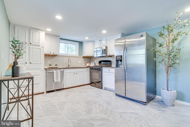 kitchen featuring backsplash, sink, appliances with stainless steel finishes, and white cabinetry