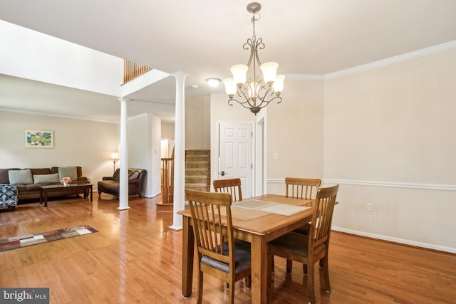 dining room featuring crown molding, wood-type flooring, an inviting chandelier, and decorative columns