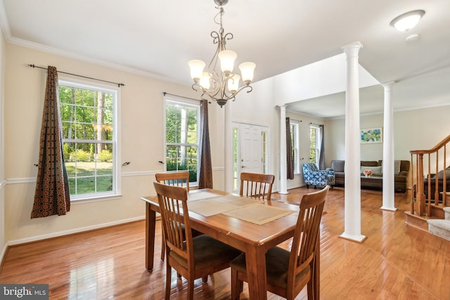 dining space featuring light hardwood / wood-style floors, a notable chandelier, ornamental molding, and decorative columns