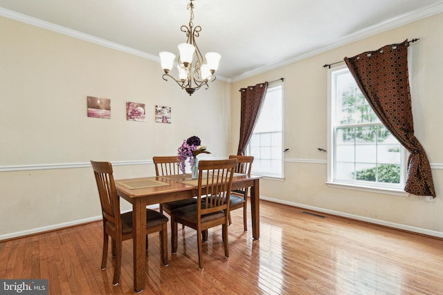 dining area featuring crown molding, a chandelier, and light wood-type flooring