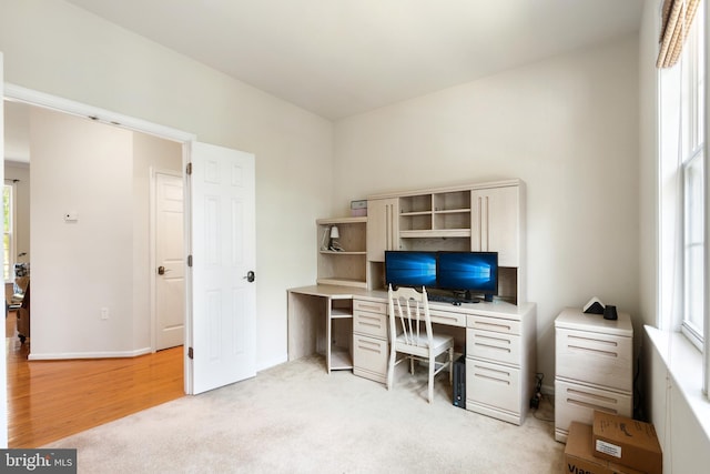 home office with light hardwood / wood-style flooring and a healthy amount of sunlight