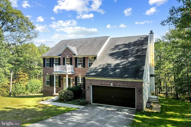 colonial inspired home featuring a front yard, a garage, and a balcony