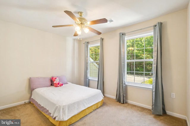 bedroom with ceiling fan, light carpet, and multiple windows