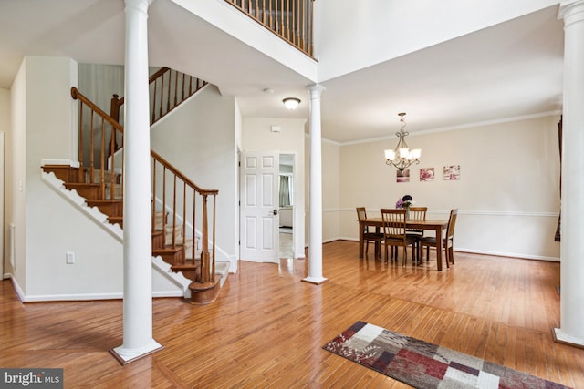 entryway with ornamental molding, a high ceiling, hardwood / wood-style flooring, and an inviting chandelier